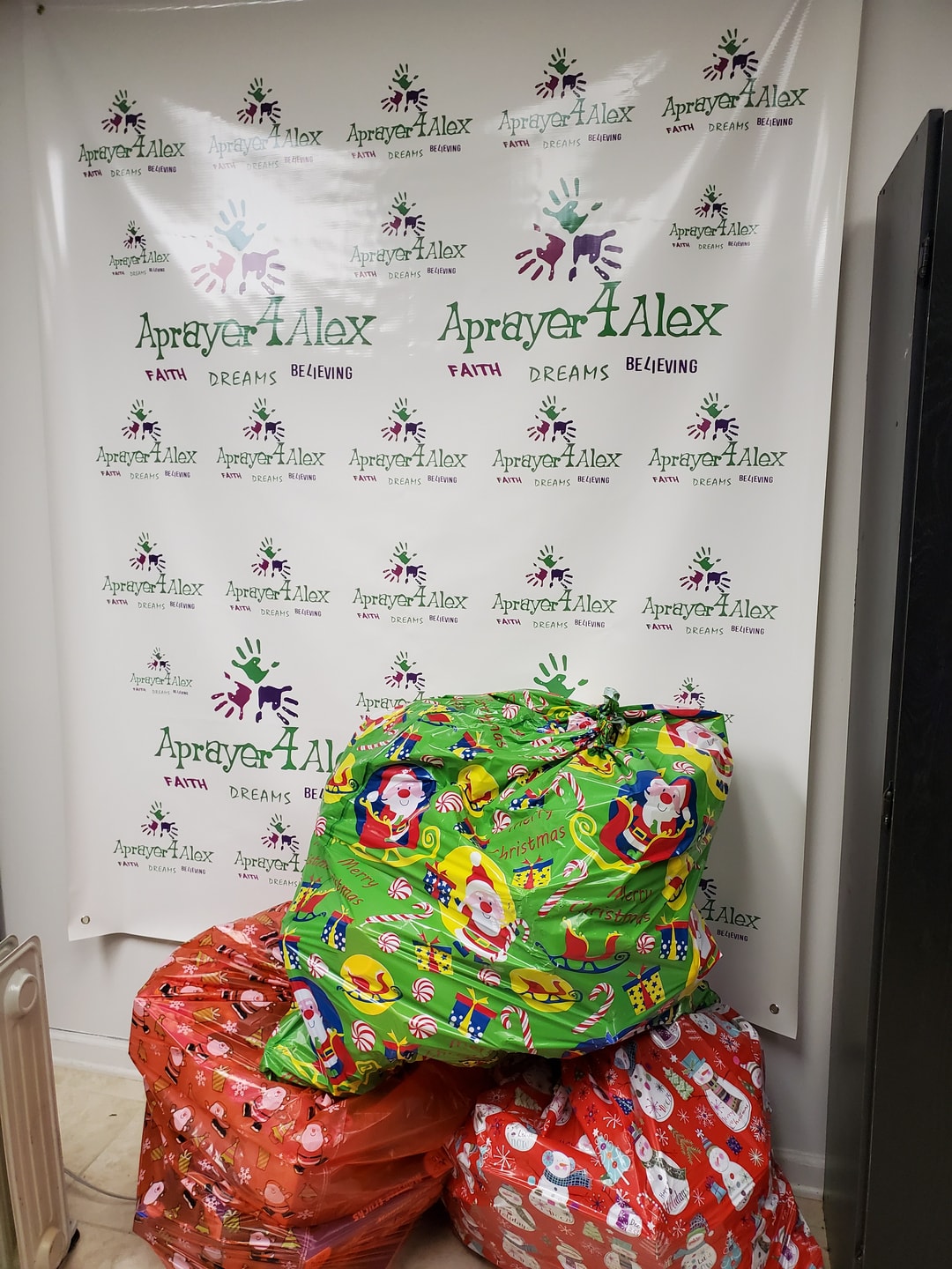Aprayer4Alex branded backdrop with holiday gift bags