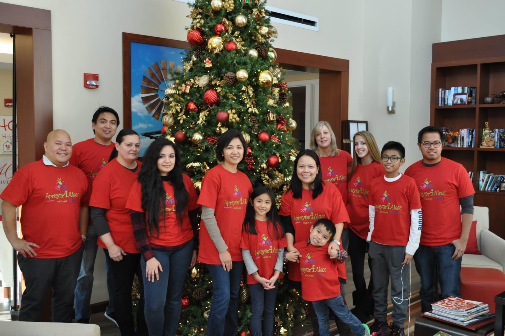 Group posing by Christmas tree in red shirts